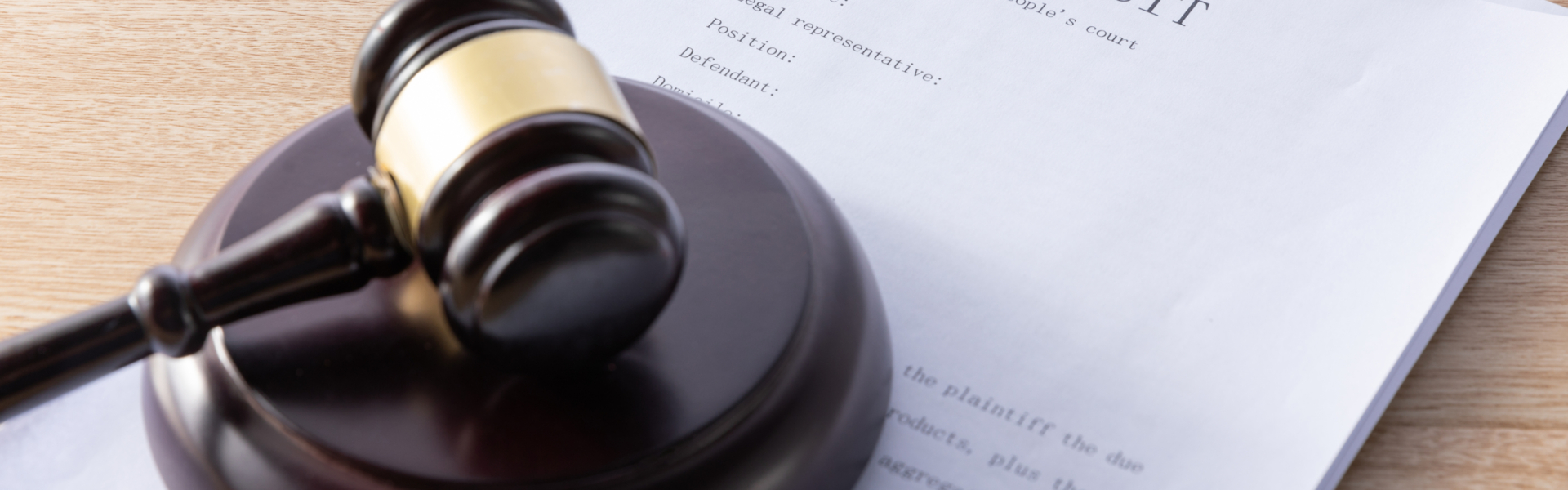 The image shows a wooden gavel resting on a legal document. The background is neutral, drawing attention to the gavel and the paperwork. The image relates to a post about ADA compliance, emphasizing the legal importance of adhering to accessibility regulations for individuals with disabilities.