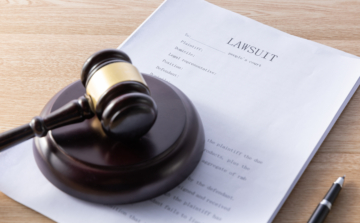 The image shows a wooden gavel resting on a legal document. The background is neutral, drawing attention to the gavel and the paperwork. The image relates to a post about ADA compliance, emphasizing the legal importance of adhering to accessibility regulations for individuals with disabilities.