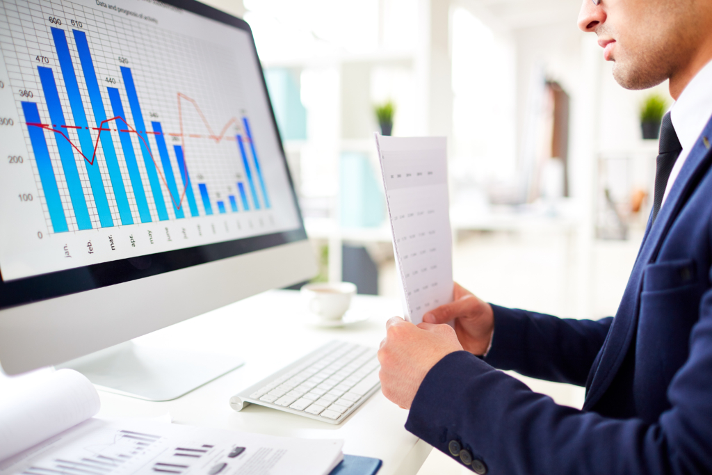 Modern financier with papers sitting in front of a computer monitor displaying a chart and graph of sales rate, focusing on ADA compliance Shopify and accessibility for online stores to improve website accessibility. The analysis highlights accessibility best practices for enhancing user experience and ensuring inclusivity in e-commerce